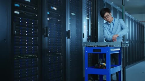 Im modernen Rechenzentrum: IT-Ingenieur, der mit Server-Racks arbeitet, verwendet Geräte, die auf einem Schubwagen liegen,