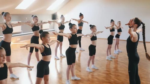 Aerobics conception. Group of female kids practicing athletic exercises together indoors.