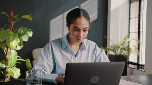 Jeune femme d'affaires afro-américaine utilisant un ordinateur portable pour taper du texte en ligne