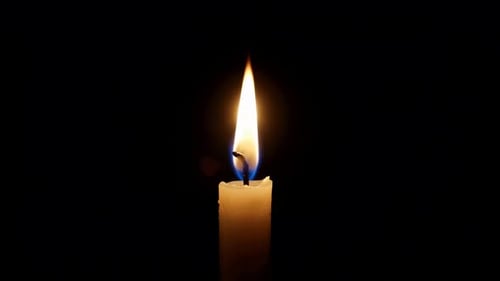 Brennende Kerzenflamme flackert auf schwarzem Hintergrund