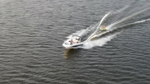 Powerboat Pulling Small Boat, Cruising Across The Sea At Daytime. aerial orbit
