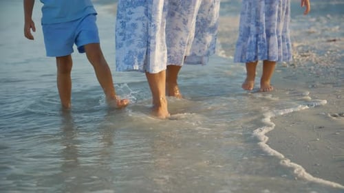 The Legs of the Family Mom and Children are Walk on Wet Sand a Sea Wave is Coming