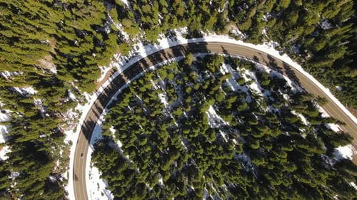 4K Aerial Drone Top Down Rise over road bend in snowy pine forest