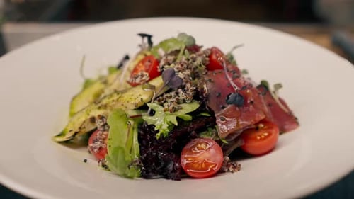A close-up of a salad with avocado jamon and cherry tomatoes prepared in the professional kitchen