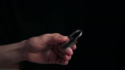 Nahaufnahme der Hände beim Öffnen eines kleinen Vorhängeschlosses mit Schlüssel