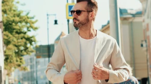 Stylish Man Walking in City Wearing Jacket and Sunglasses