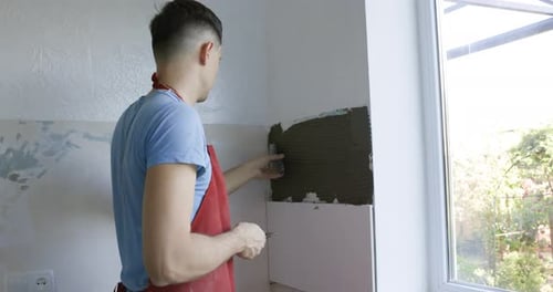 Man Installing White Tiles Indoors
