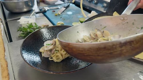 Cuisiner des pâtes spaghettis avec des palourdes dans la poêle d'un restaurant
