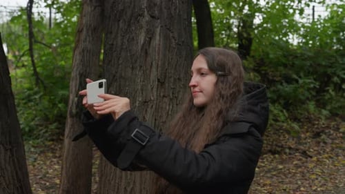Woman Pauses During Walk to Photograph Serene Forest Landscape Female Hiker Captures Candid Moments