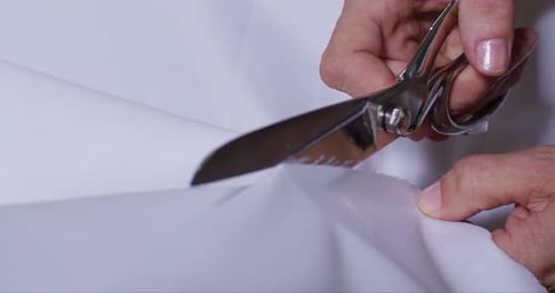Hands Cutting White Fabric with Scissors Close Up