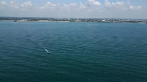 Aerial drone shot capturing the delicate balance of a fisher boat on the gentle ocean waves.