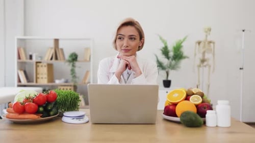 Smiling woman with computer and vegetables in office