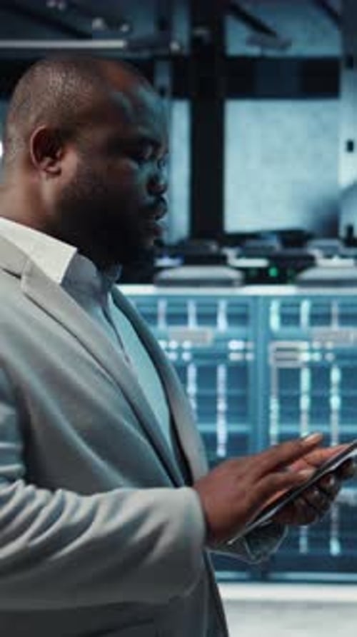 Vertical Video Technician Working in High Tech Server Hub Analyzing Data on Tablet