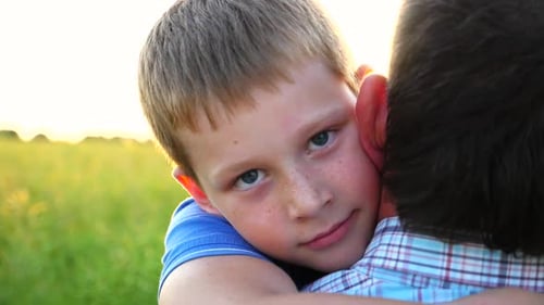 Boy Hugs Adult Outside on Sunny Day