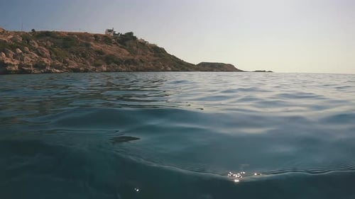 Surface of water with coastal rocks, Low-angle shot, backlight, seascape