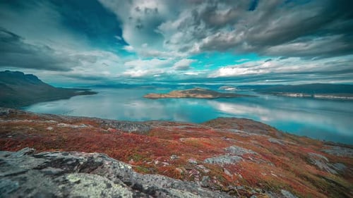Im Zeitraffervideo wirbeln stürmische Wolken über dem ruhigen, spiegelglatten Fjord und der Herbsttundra.