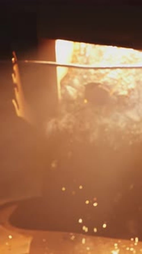 Skilled Workers Pouring Molten Metal in a Large Industrial Foundry with Safety Equipment Stock Clip