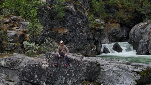 Sentado en una roca junto al río en el bosque en algún lugar de Noruega