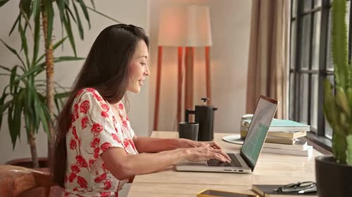 Happy Woman Working in Home Office and Typing on Keyboard of Laptop Computer