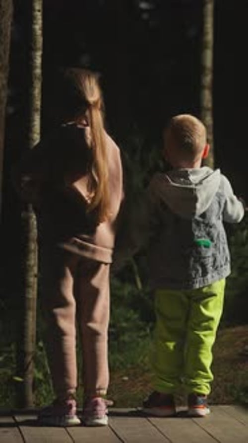 Children on Ground Among Wild Dark Forest at Twilight