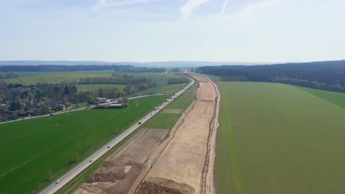 Luftaufnahme einer im Bau befindlichen Autobahn mit Arbeitszonen und Ausrüstung.