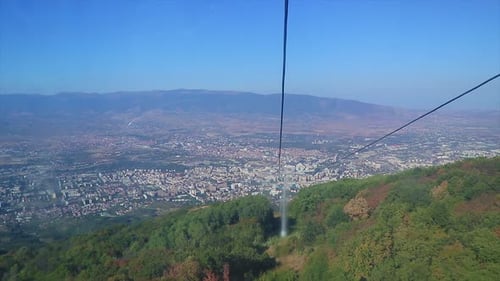 Aerial view of a city from a cable railway coming down from a mountain.