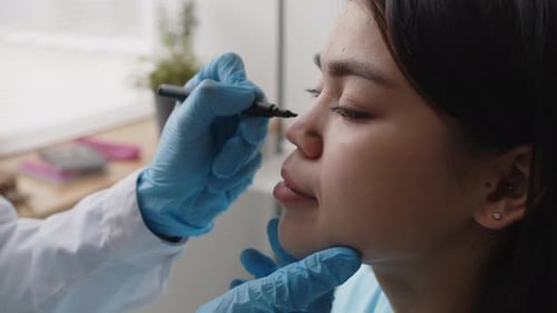 Hands of Plastic Surgeon Marking Face of Female Patient before Rhinoplasty