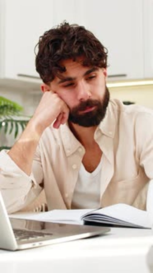 Tired Man Working at Laptop with Coffee Indoors