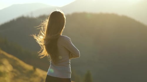 Lonely Woman Hiker Standing Alone on Grassy Mountain Top Enjoying View of Sunset Nature on