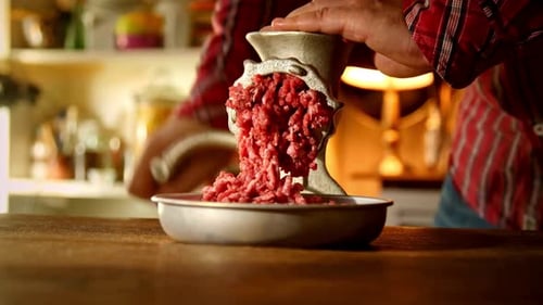 Close-Up of Man Mincing Raw Meat with Manual Grinder in Kitchen
