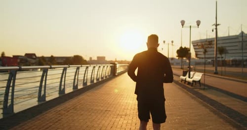 Young Athletic Man Jogging on a City Street at Golden Sunset