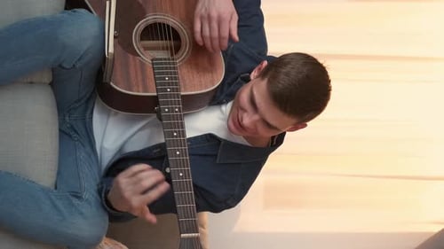 Young Adult Plays Acoustic Guitar at Home
