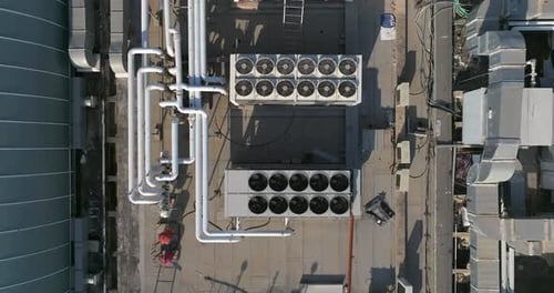 Industrial building rooftops with vents and pipes lined across, Top down view