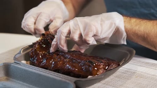 Guy mange de délicieuses côtes de porc cuites avec de la sauce. En gros plan