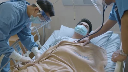 Hospital Doctor And Nurse Checking The Male Patient's Heartbeat And Blood Tube