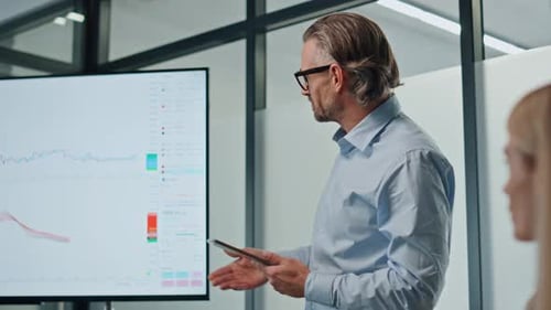 Confident businessman pointing screen showing project to team in modern office