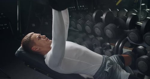 Man Bodybuilder Doing Bench Press with Heavy Dumbbells in Gym