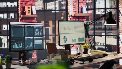 Monitores de computadora en el escritorio de la oficina que muestran paneles de análisis de datos