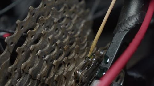 Bike chain lubricant dripped onto links in maintenance shop closeup