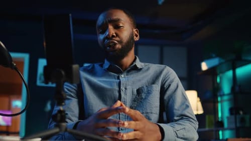 Young Man Vlogging in Blue-Lit Room