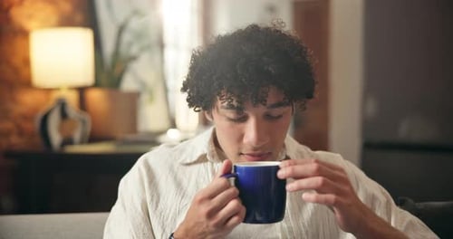 Smiling Man Enjoying Warm Drink in Living Room