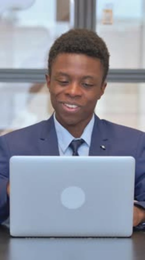 Young Man in Suit Talking to Laptop in Office