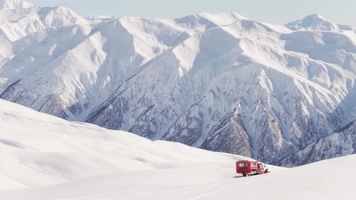Snowy Mountains and Red Snowcat Grooming Ski Slopes