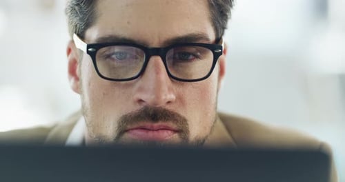 Nahaufnahme eines seriösen, denkenden und fokussierten professionellen Mannes, der in seinem Büro auf einen Laptop schaut