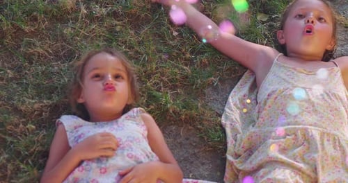 Authentic shot of two cute little girls sisters are lying on the grass and having fun playing with