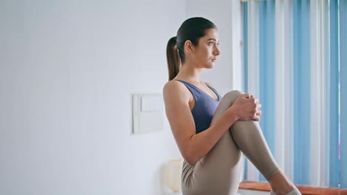 Woman Stretching Quadriceps in Bright Home Gym