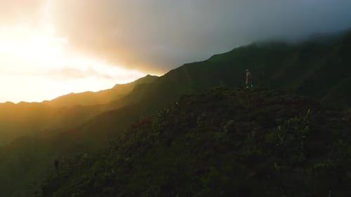 Person on Tropical Mountain Top at Sunset