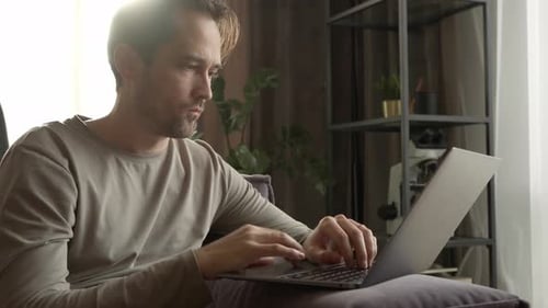 Man Relaxing on Couch Using Laptop