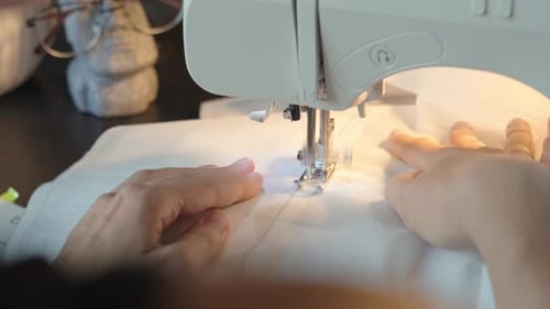 Close up of female hands using sewing machine to sew fabric