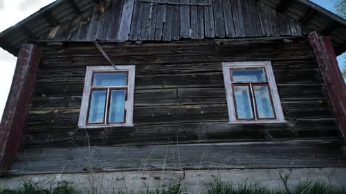 Old Wooden House with Two Windows Showing Blue Sky in a Slavic Village